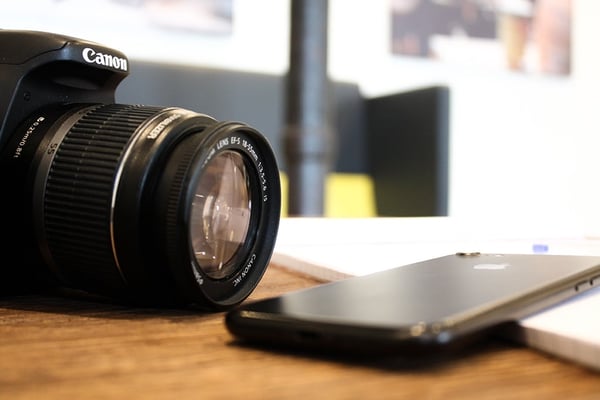 Canon camera next to a smartphone
